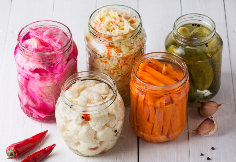 Fermented vegetables. Homemade marinated cabbage with carrot and cucumbers, sauerkraut sour in glass jars. Preserved canned vegetables, superfoods and vegetarian food.