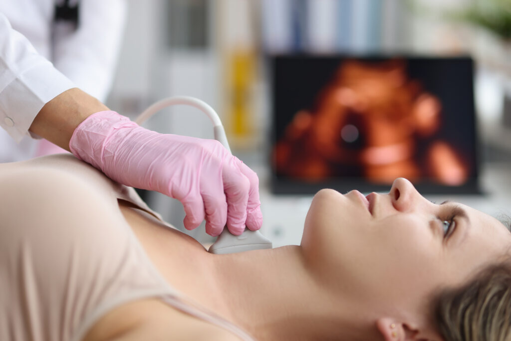 Portrait of doctor endocrinologist doing ultrasound of thyroid gland in clinic. Ultrasound sensor over patients neck with gel. Diagnostics and medicine concept