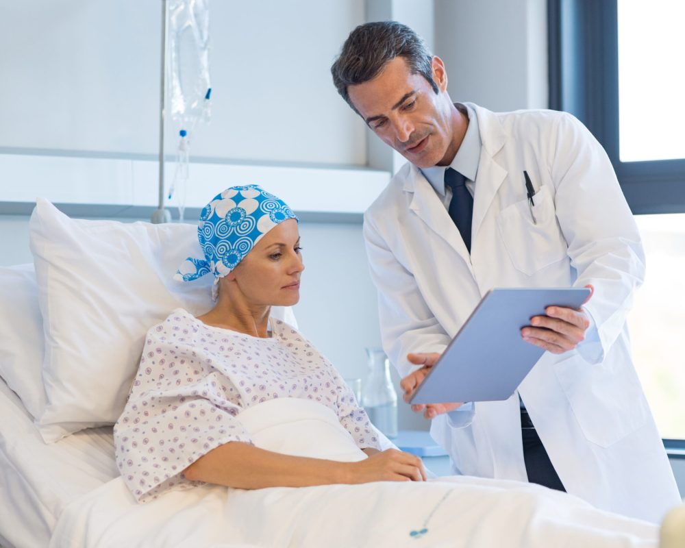 Doctor telling to patient woman the results of her medical tests. Doctor showing medical records to cancer patient in hospital ward. Senior doctor explaint the side effects of the intervention.