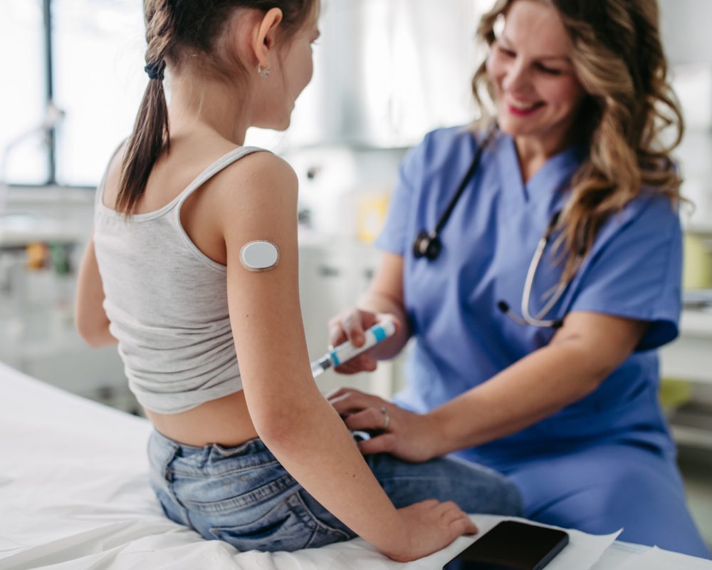 Nurse injecting insulin in diabetic young girl belly. Close up of young girl with type 1 diabetes taking insuling with syringe needle.