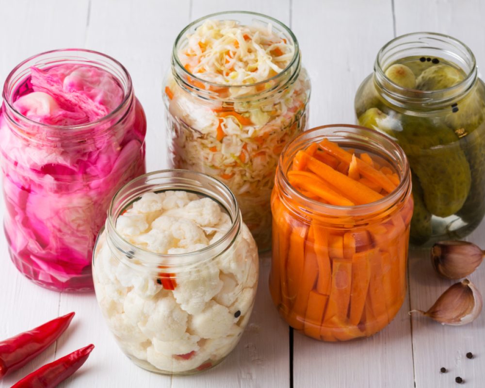 Fermented vegetables. Homemade marinated cabbage with carrot and cucumbers, sauerkraut sour in glass jars. Preserved canned vegetables, superfoods and vegetarian food.