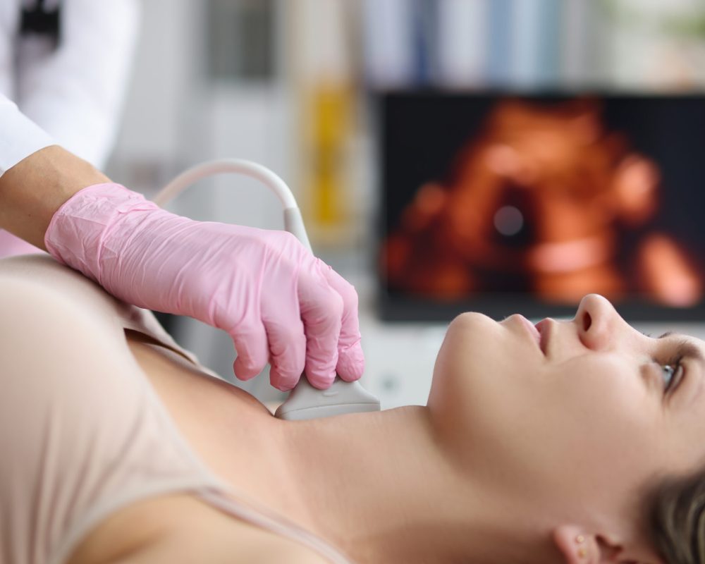 Portrait of doctor endocrinologist doing ultrasound of thyroid gland in clinic. Ultrasound sensor over patients neck with gel. Diagnostics and medicine concept