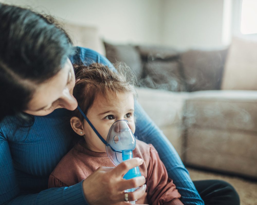 Mother helps her little girl to makes inhalation at home.During coronavirus COVID-19